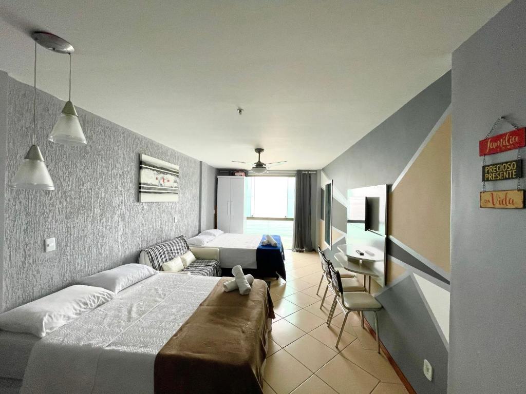 a bedroom with a bed and a desk and a television at Loft Prainha Vista Mar in Arraial do Cabo