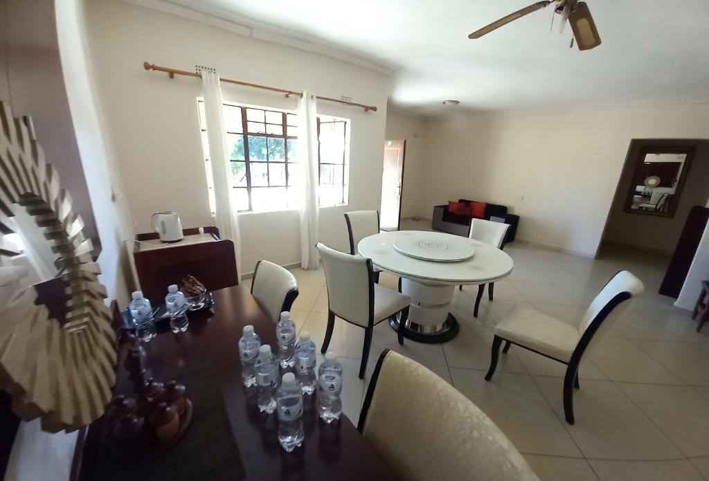 a dining room with a table and chairs and a room with a window at Kandjo's Bed and Breakfast in Palatswe
