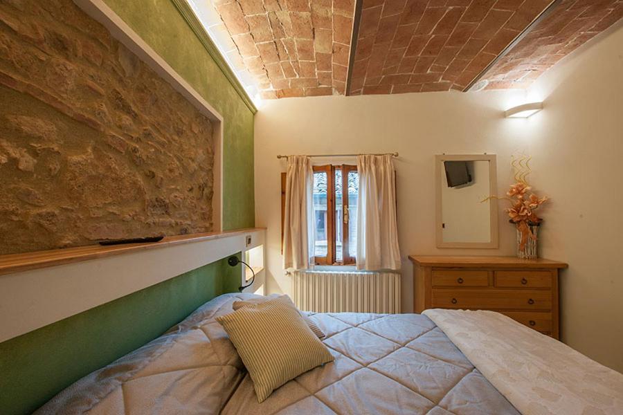 una camera con un letto in una stanza con una finestra di Affittacamere Il Bastione 27 a Volterra