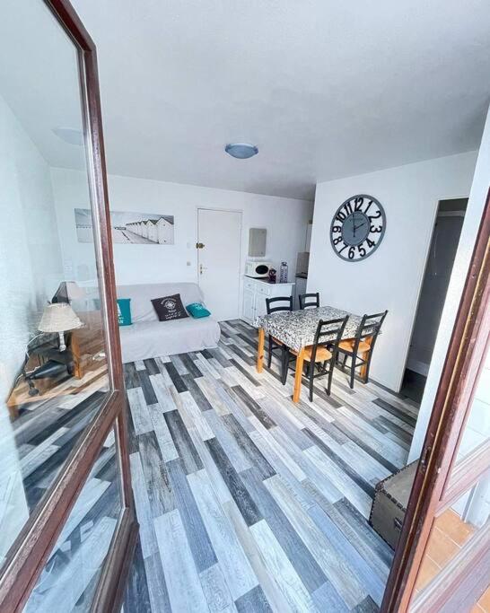 - un salon avec une table et une horloge murale dans l'établissement SAINT GEORGES DE DIDONNE Baie de l océan les dauphins, à Saint-Georges-de-Didonne