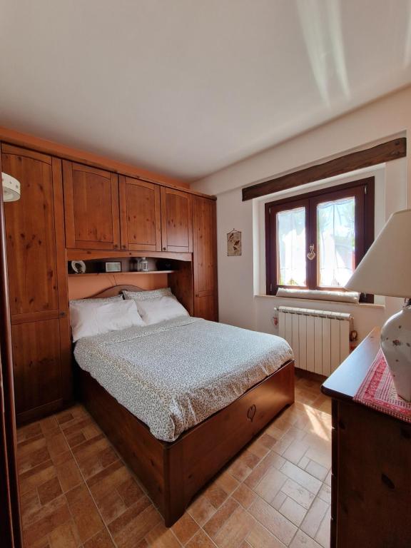 a bedroom with a bed with wooden cabinets and a window at La Libellula apartment (Il tuo Chalet sul colle) in Castel di Sangro