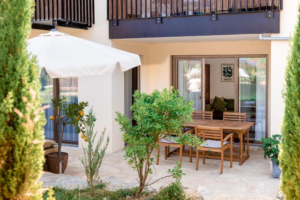 a patio with a wooden table and an umbrella at Ferienwohnung`Akazie` mit Terrasse auf dem Bodanrück in Radolfzell am Bodensee