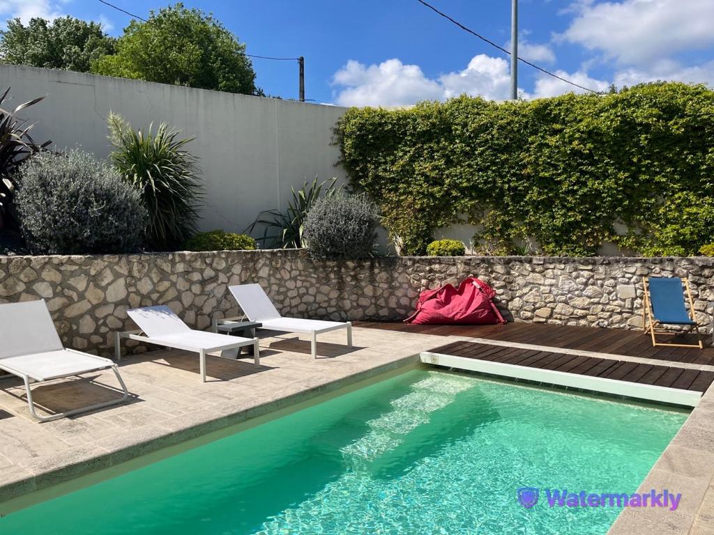 - une piscine avec 2 chaises à côté d'un mur dans l'établissement Villa climatisée avec piscine à St Remy, à Saint-Rémy-de-Provence