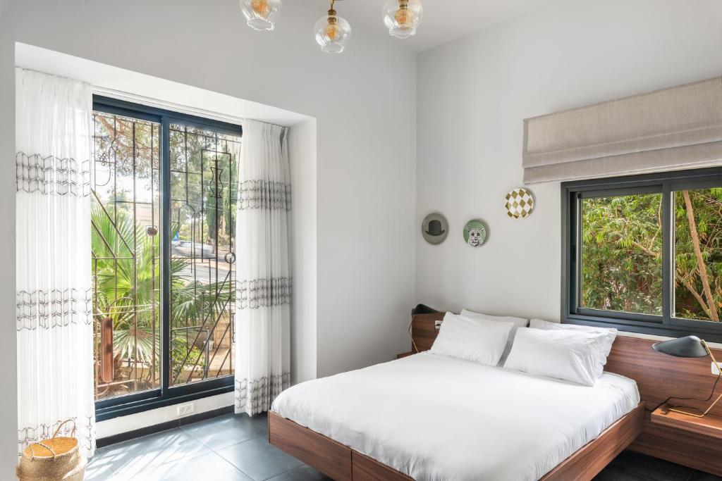 Carmel Suites by Olala Homes في حيفا: غرفة نوم بسرير ونوافذ كبيرة