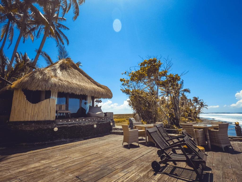 una terrazza con sedie e una capanna sulla spiaggia di Beachfront Villa Nixie and the Sea Tabanan a Tabanan