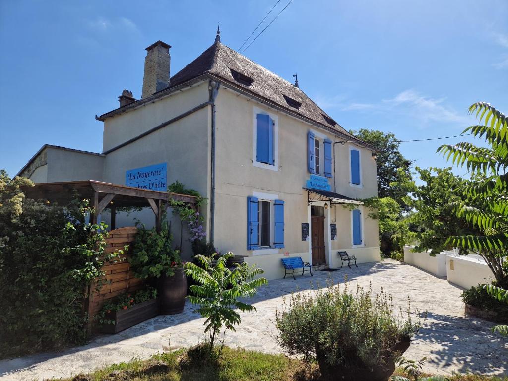 Biały dom z niebieskimi oknami i werandą w obiekcie La Noyeraie Rocamadour w mieście Rocamadour
