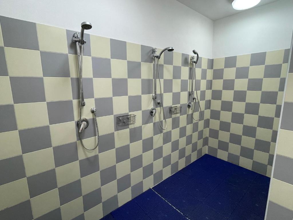 a bathroom with checkered walls and shower stalls at Lunga Via Delle Dolomiti in Calalzo