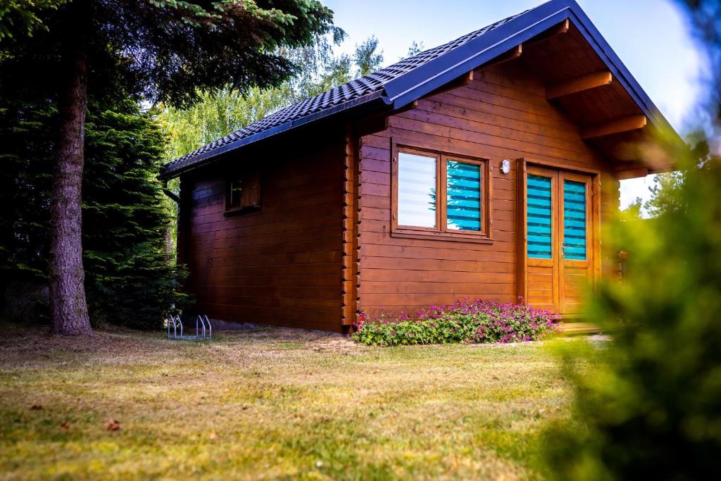 a small wooden cabin with a window and trees at Domek Między Wodą in Międzywodzie