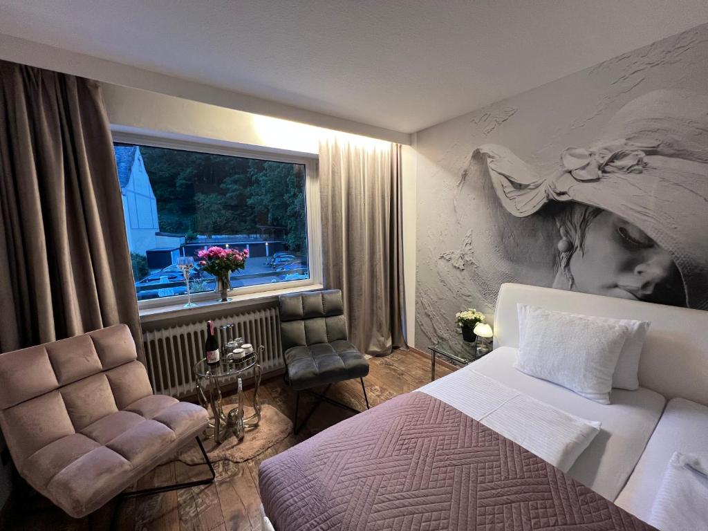a bedroom with a bed and a window and a chair at Health and Spa by Doro im Hotel am Schwanenweiher in Bad Bertrich