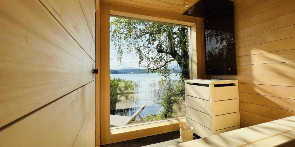 Zimmer mit einem Fenster und Blick auf das Wasser in der Unterkunft Naturel Chalet am Faaker See in Faak am See