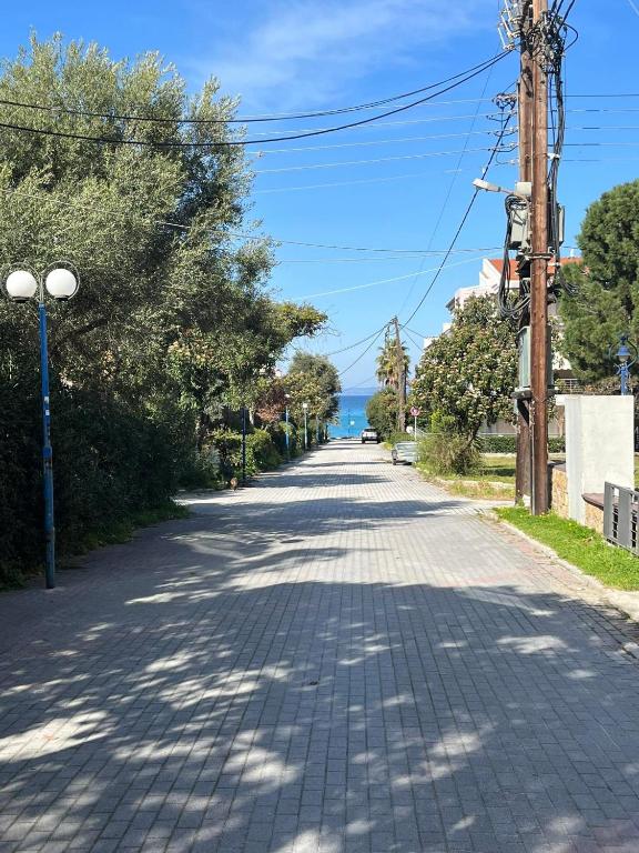 una strada vuota con alberi e l'oceano sullo sfondo di Apartment beside the sea a Hanioti