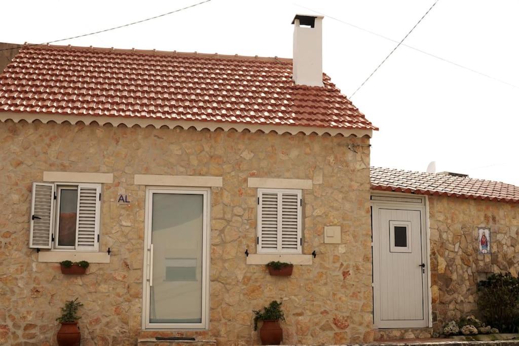 a stone house with two windows and a door at Casa Emília & Alda in Juncal