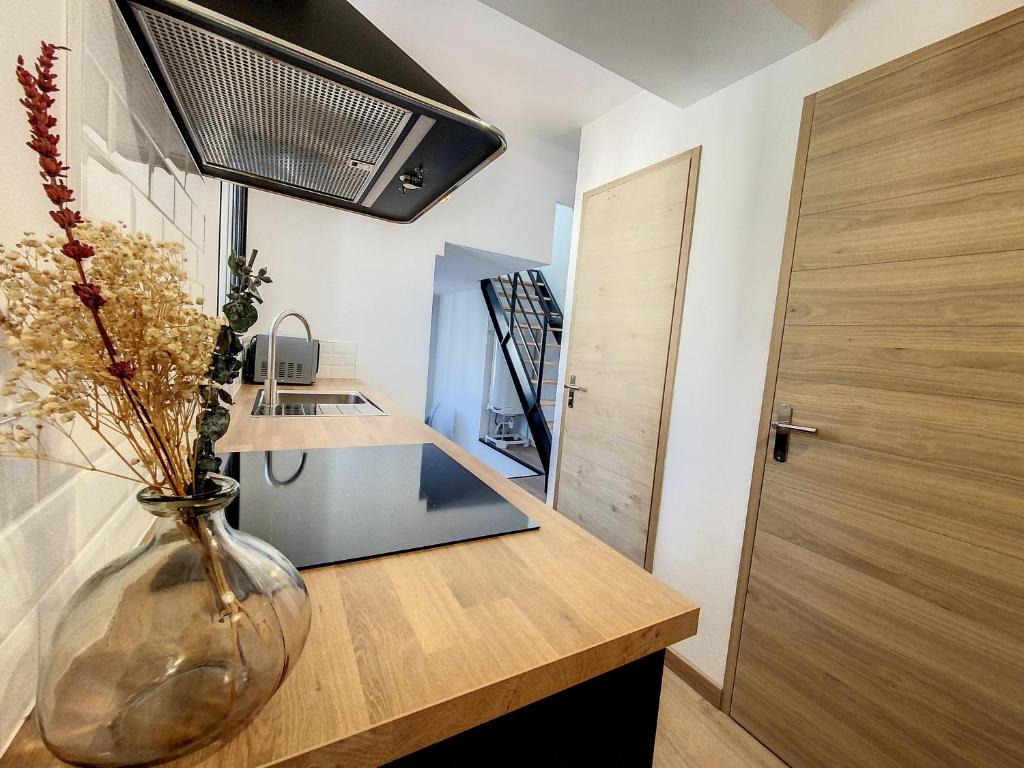 a vase with flowers on a wooden counter in a kitchen at Au Duplex indus/chic de Breteuil in Breteuil