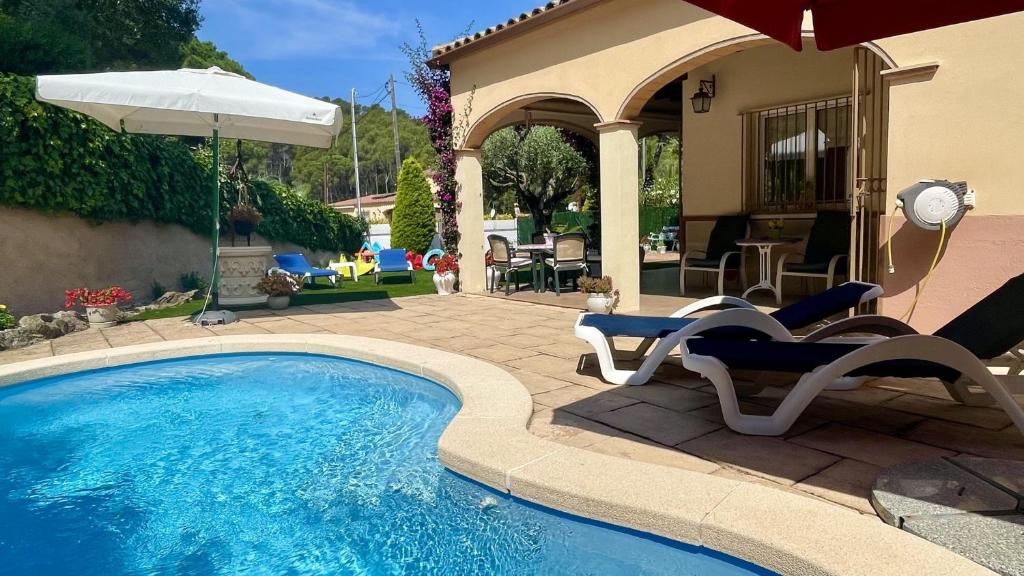 a swimming pool with two chairs and an umbrella at Villa Pineda 5 in Pals