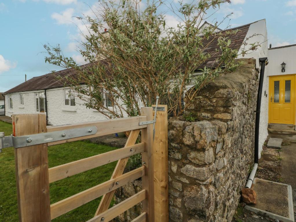 a wooden fence with a tree on top of a stone wall at Primrose Cottage in Tenby