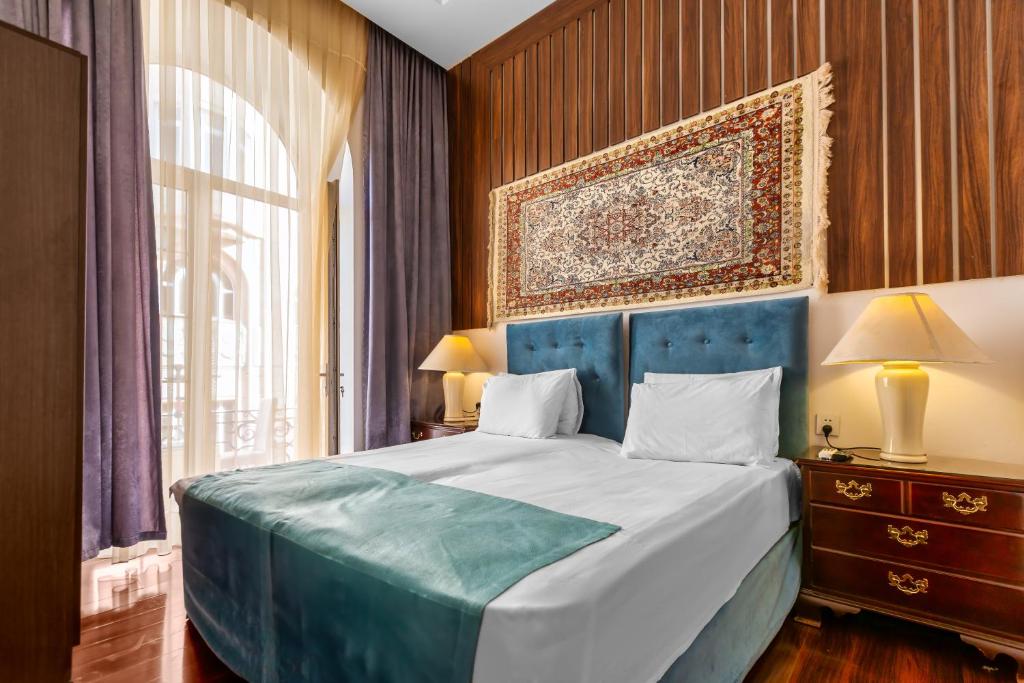 - une chambre avec un lit bleu et une grande fenêtre dans l'établissement Lacasa Nizami Street, à Baku