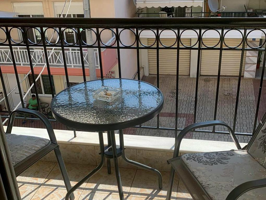 a glass table and two chairs on a balcony at Anna-Apartment in Nea Moudania