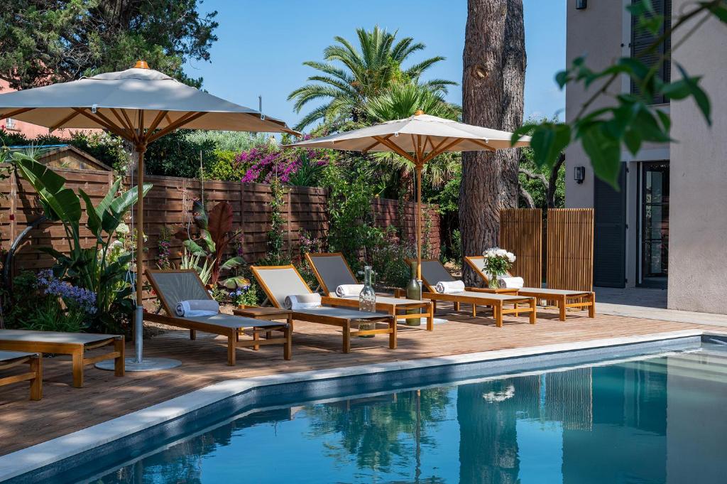 a swimming pool with lounge chairs and umbrellas next to a swimming pool at Lou Cagnard in Saint-Tropez