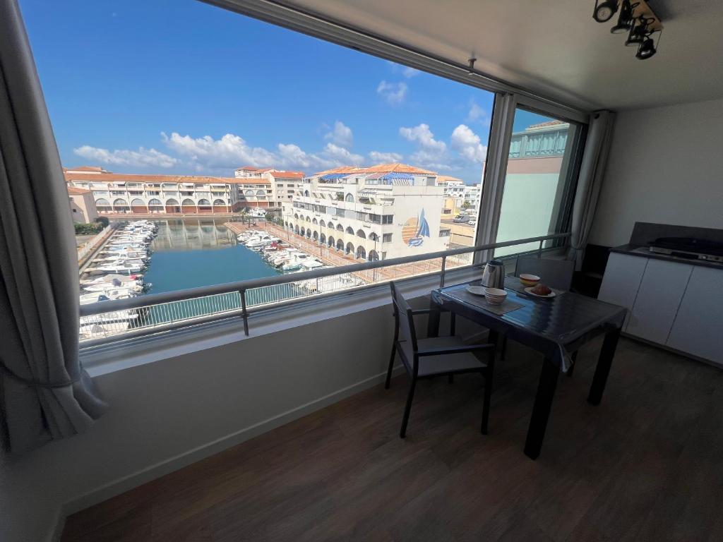Cette chambre dispose d'une table et d'une fenêtre avec vue sur le port. dans l'établissement Appartement 5 personnes Sète, à Sète