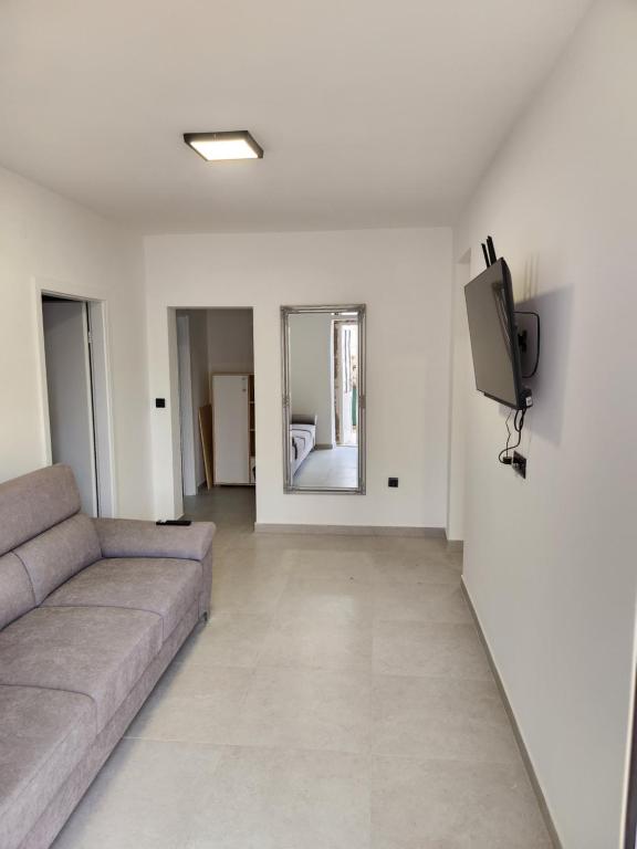 uma sala de estar com um sofá e uma televisão na parede em H&D Apartment em Sumartin