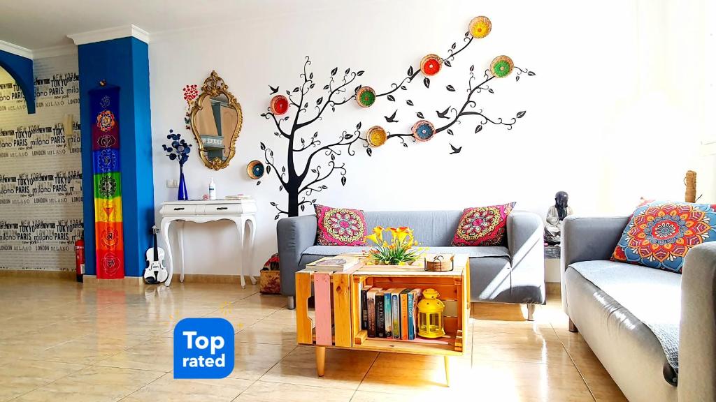 a living room with a couch and a tree with eggs on the wall at "Burrero Bay Høme" Geniu's Best Selection - Airport Homely Stays in Playa del Burrero