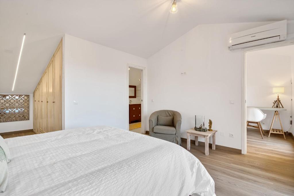 a white bedroom with a bed and a chair at Blue Greenwich Port in Altea