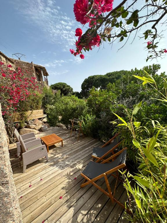 a wooden deck with chairs and a table and flowers at Hôtel Ambassador Palombaggia in Porto-Vecchio