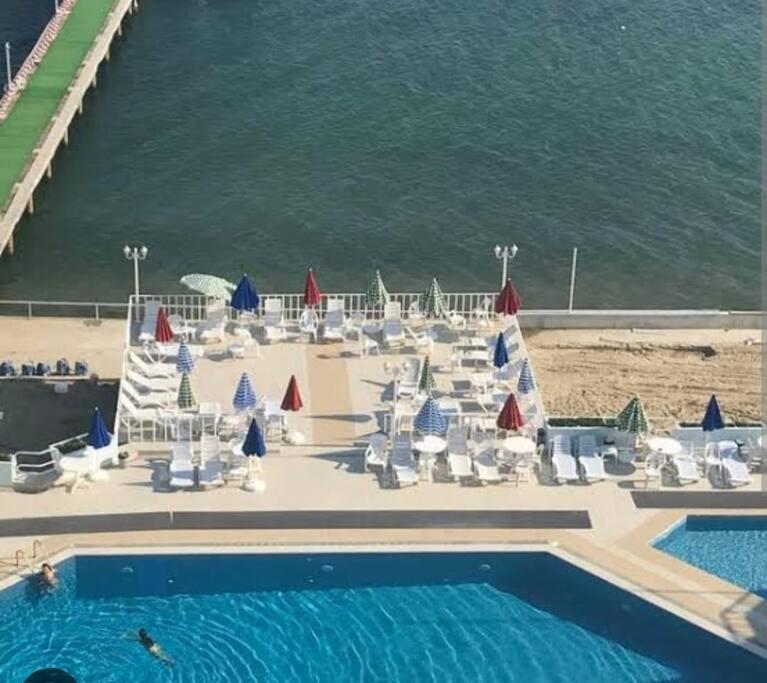 a pool with chairs and umbrellas next to the ocean at Cozy apart / Rahatlamanın zamanı in Silivri