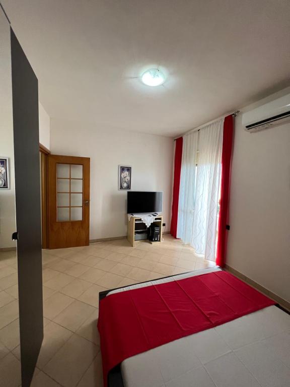 una sala de estar con cortinas rojas y una habitación con TV en Marina Appartamenti, en Vlorë