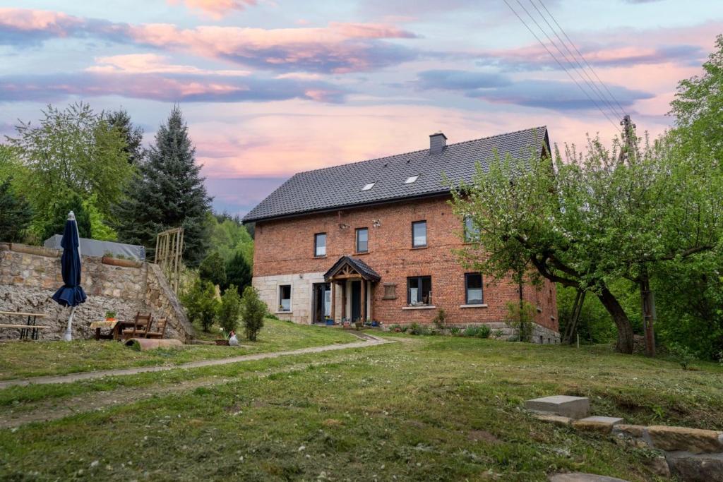 una casa de ladrillo en una colina con un patio en Agroturystyka Ziemia Obiecana, en Nielestno