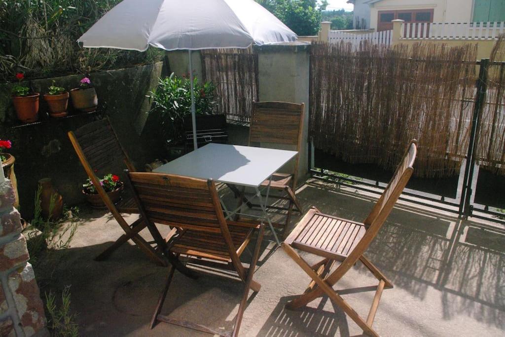 a table and chairs with an umbrella on a patio at appartement autonome in Prémilhat
