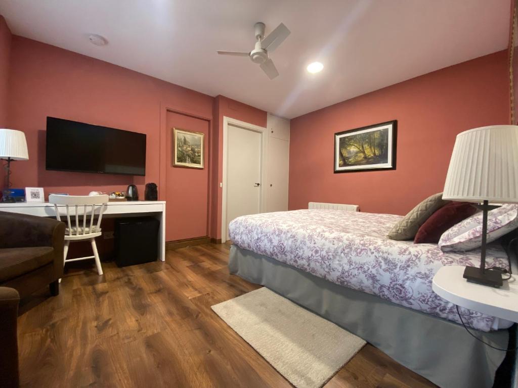 um quarto com uma cama, uma secretária e uma televisão em Escloper B&B em Sant Juliá de Vilatorta