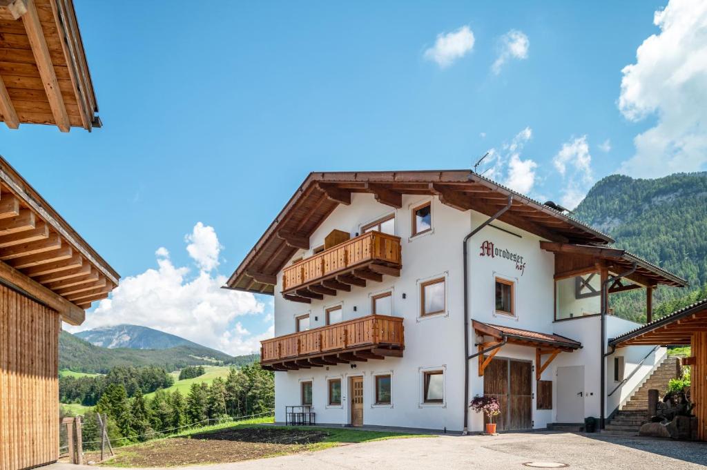 a building with wooden balconies and mountains in the background at Morodeserhof Apt Bühlen 2 in Castelrotto