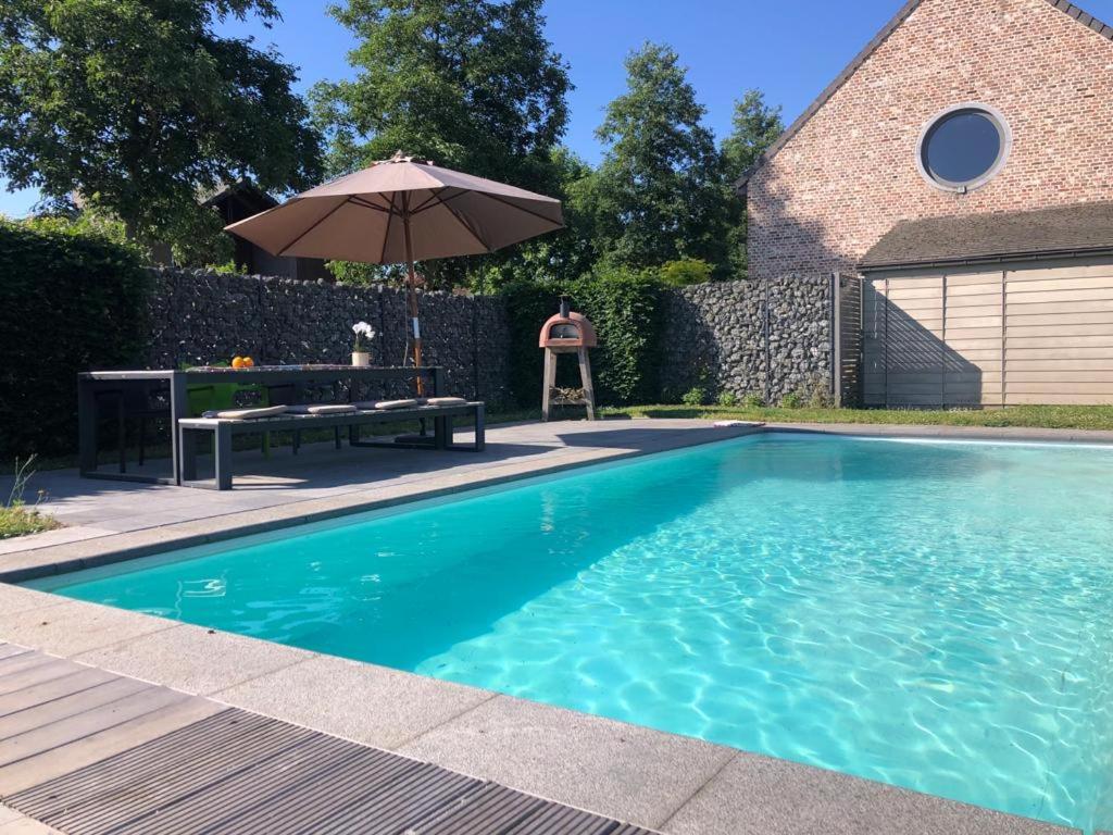 - une piscine avec une table et un parasol dans l'établissement landelijke villa met zwembad en gezellige openhaard, à Zemst