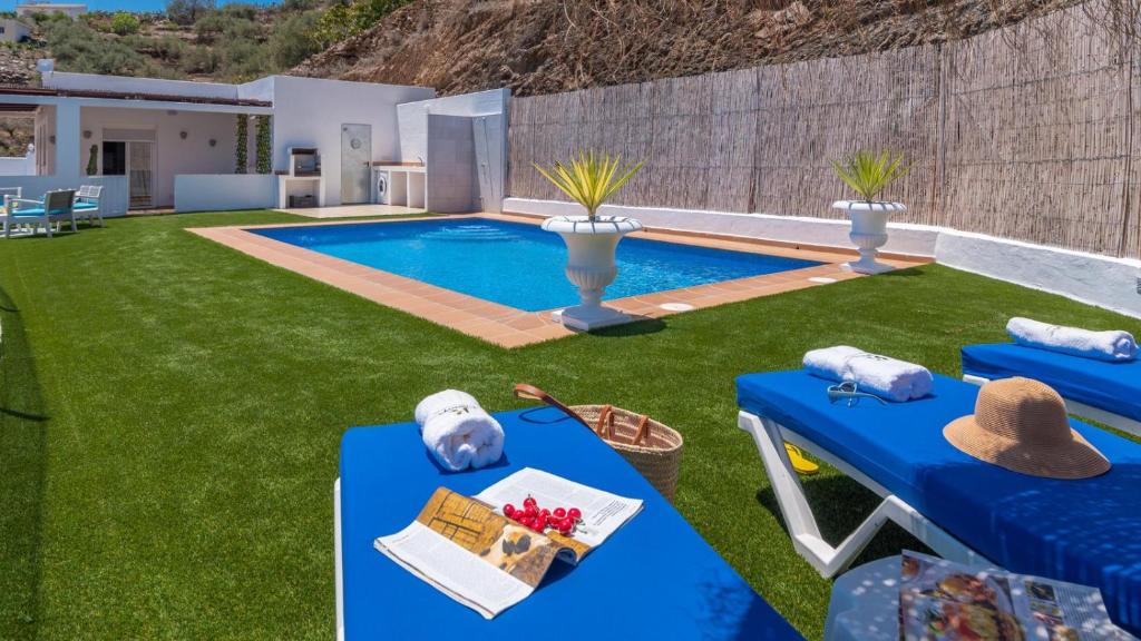 een achtertuin met een zwembad met een blauwe tafel en stoelen bij Villa Diego Torrox by Ruralidays in Torrox