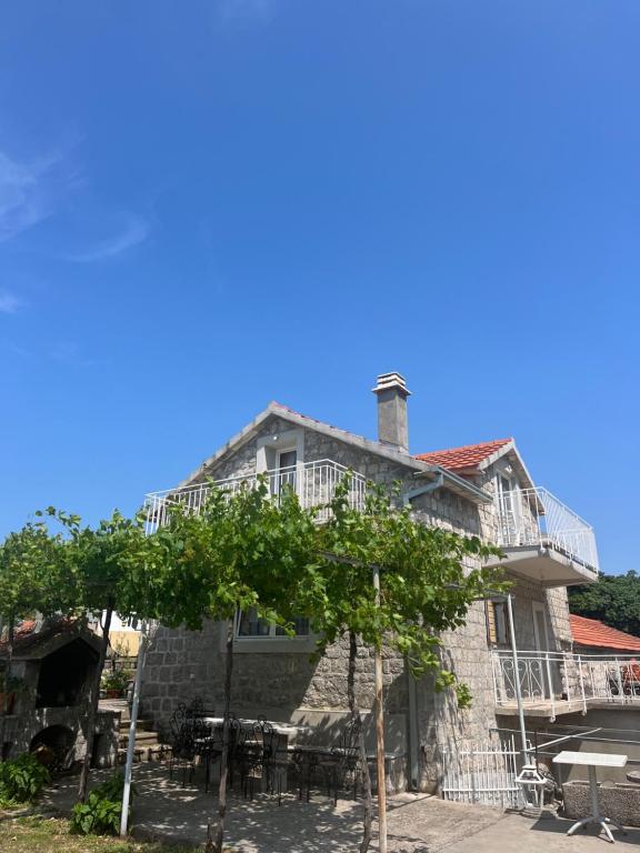 an old house with a patio and trees in front at Luštica Old House in Tivat