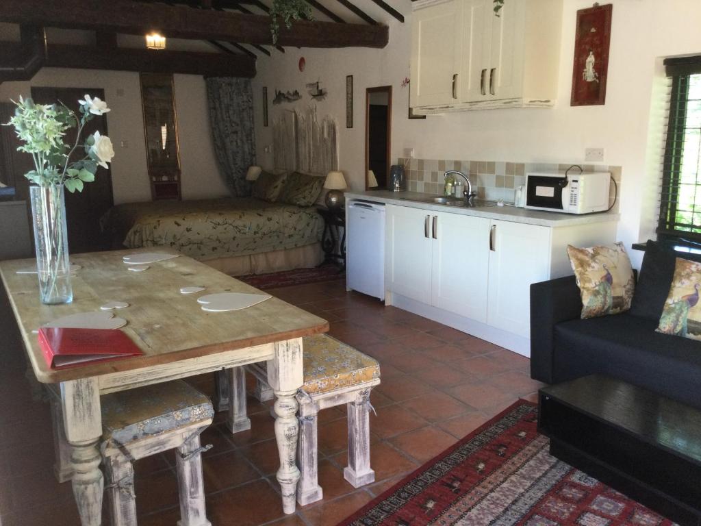eine Küche und ein Wohnzimmer mit einem Tisch und einem Sofa in der Unterkunft The Garth Guest Suite Studio Cottage in Lingfield