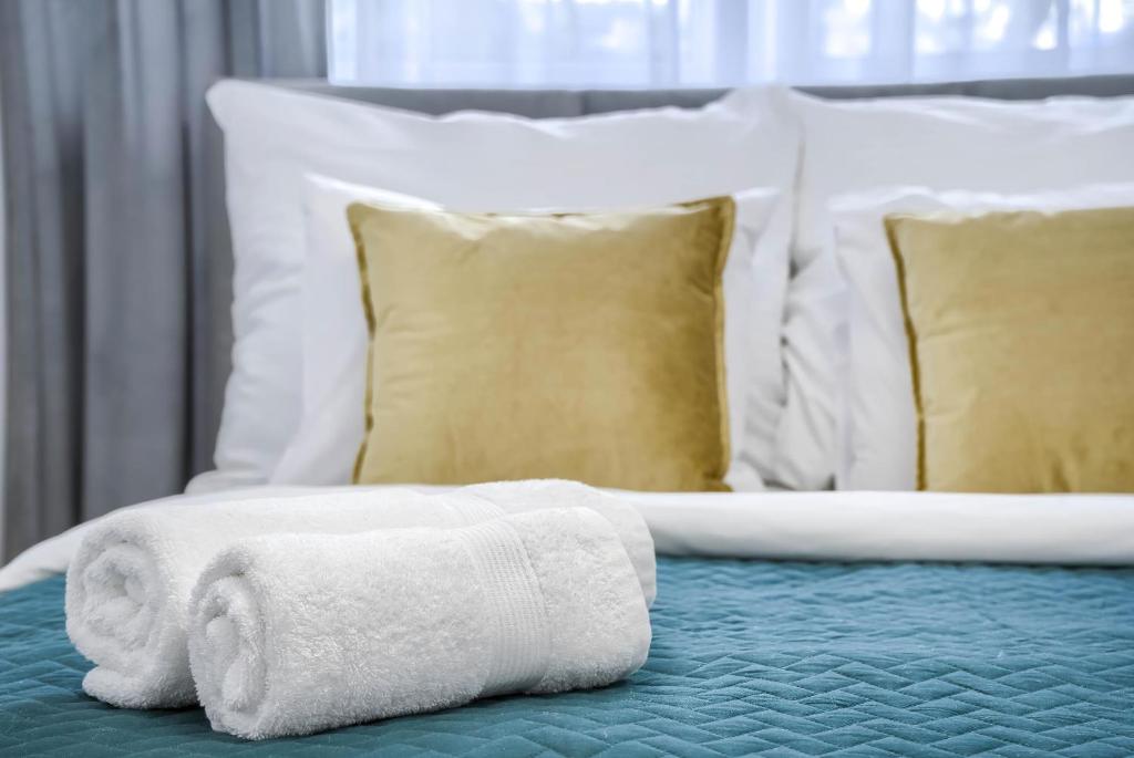 ein weißes Handtuch auf einem Bett mit Kissen in der Unterkunft Corolla Apartments Solidarności 96 in Warschau