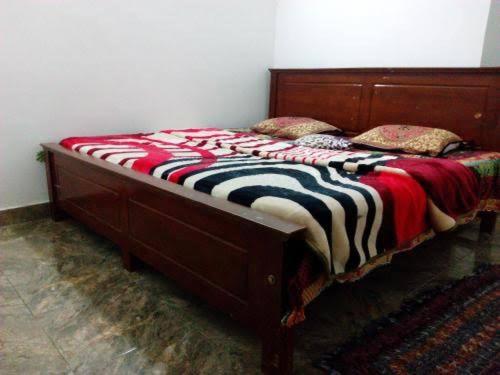1 cama con marco de madera en un dormitorio en Tourist misty holiday resort, en Pattipola