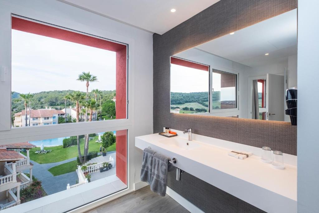a bathroom with a large window and a white sink at HG Jardín de Menorca in Son Bou