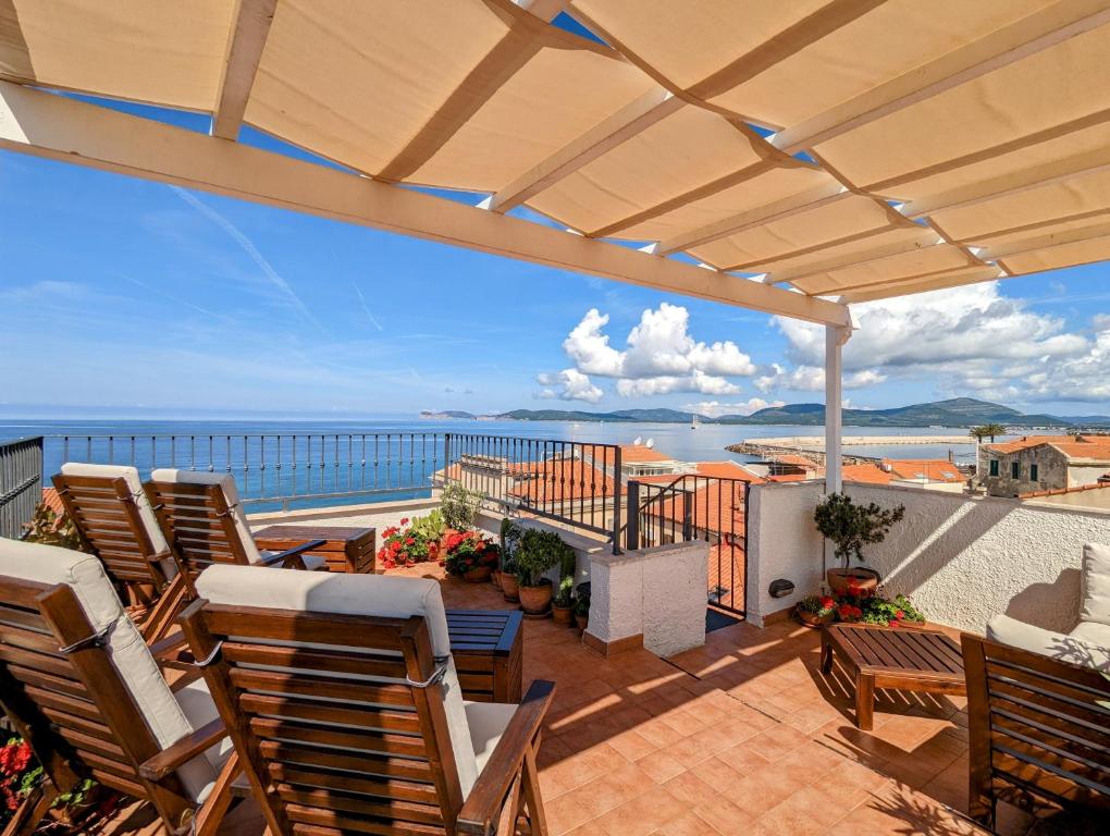 un patio con sillas y vistas al océano en Panorama Guest House en Alguer