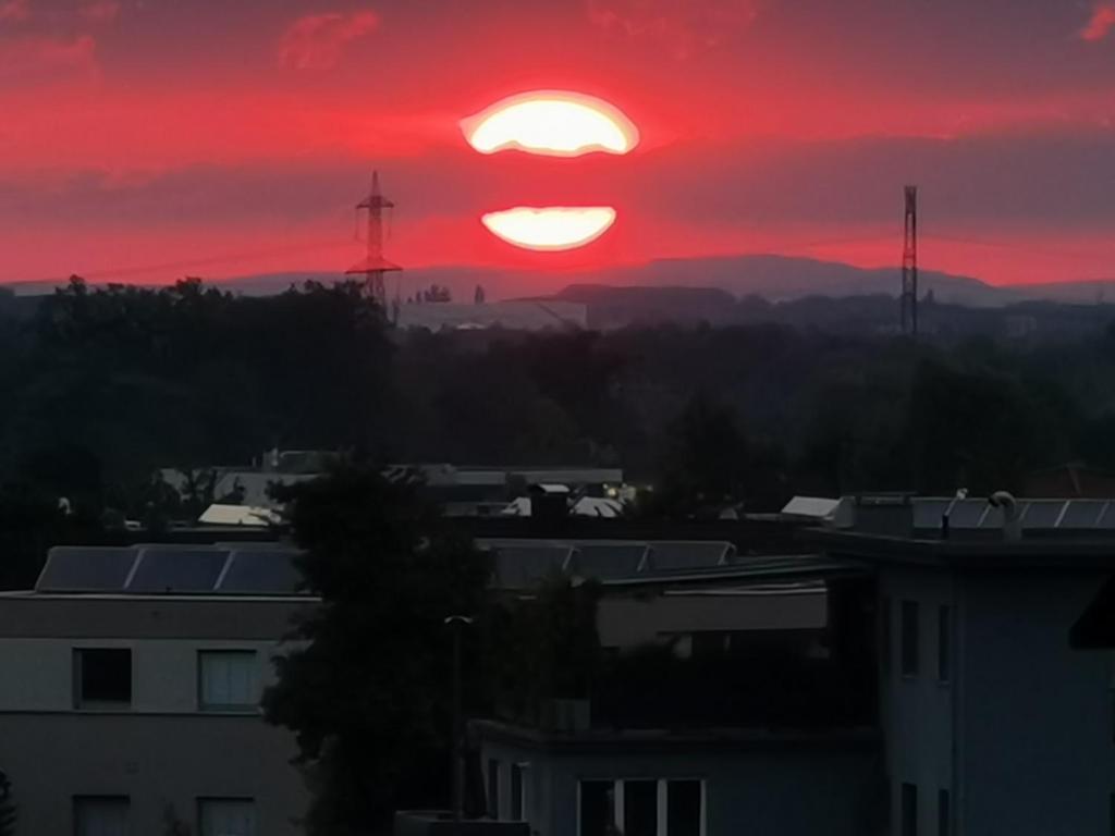 ドルンビルンにあるSkyline klimatisierte Dachgeschoss-Wohnung in Dornbirn mit Blick ins Rheintalの赤い空の都市に沈む夕日