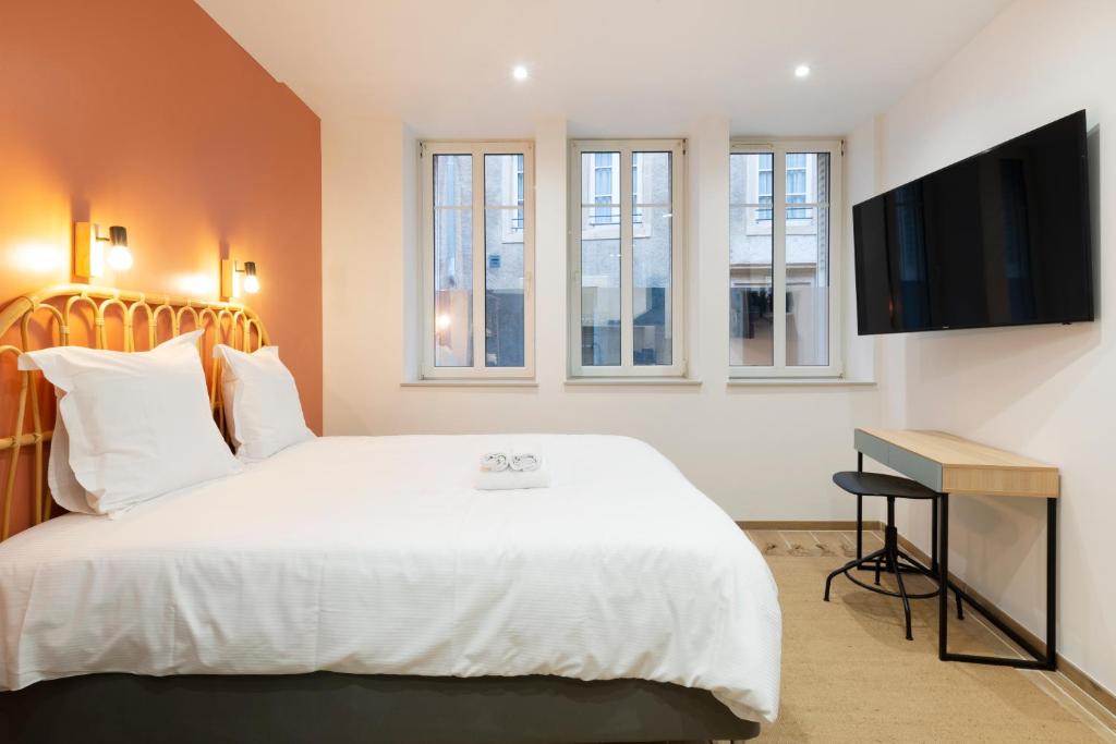 een slaapkamer met een wit bed en een flatscreen-tv bij L'Annexe Metz Cathédrale in Metz