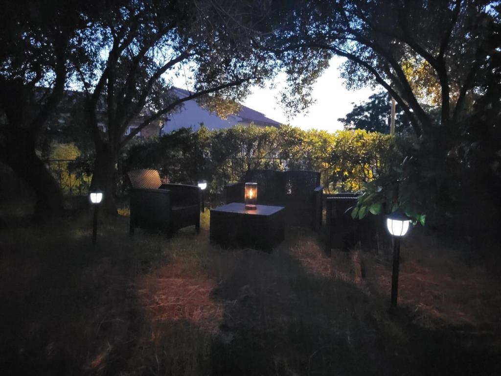 a table and chairs in a yard at night with lights at Apartman Padova in Rab