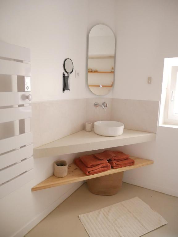 une salle de bain avec un lavabo et un miroir dans l'établissement Le Clos des Confidences, à Grignan