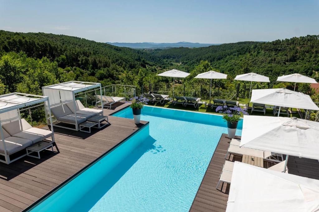 Elle offre une vue sur la piscine bordée de chaises et de parasols. dans l'établissement Domaine de Chalvêches Hôtel SPA 4*, à Faugères