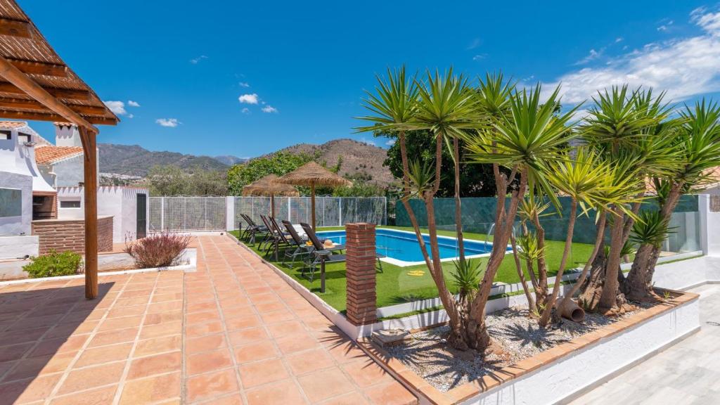 a patio with palm trees and a swimming pool at Villa Tablazos 29 Nerja by Ruralidays in Frigiliana