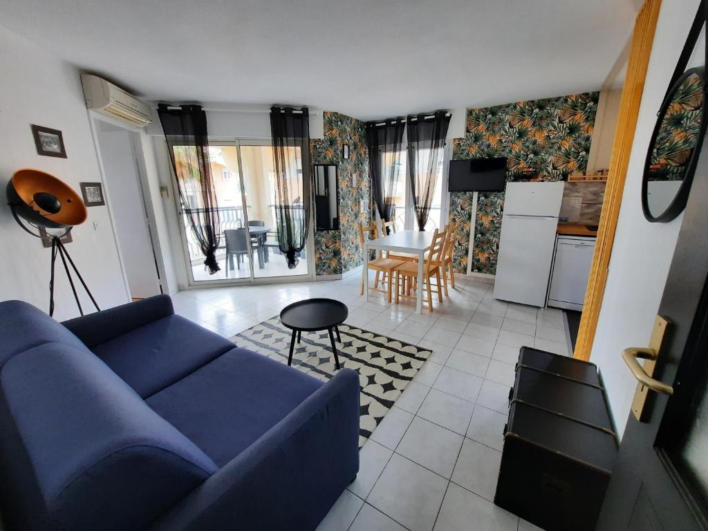 een woonkamer met een blauwe bank en een keuken bij Coeur Marina climatisé terrasse parking in Fréjus