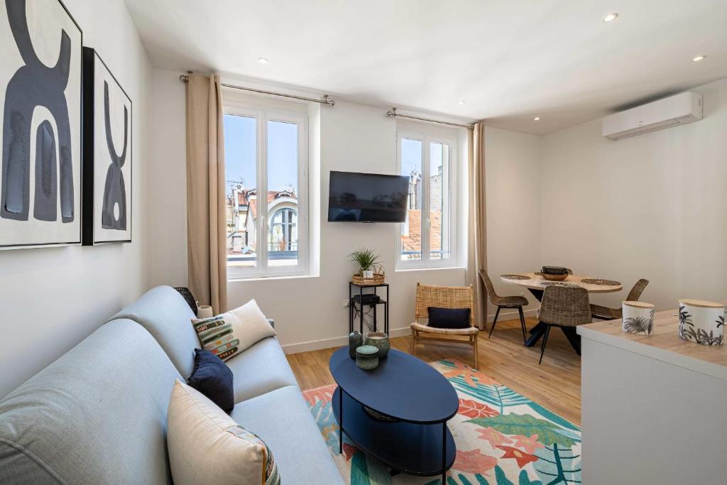 ein Wohnzimmer mit einem blauen Sofa und einem Tisch in der Unterkunft Cosy flat 100m from the beach - Carré d'Or - 1BR2p in Cannes