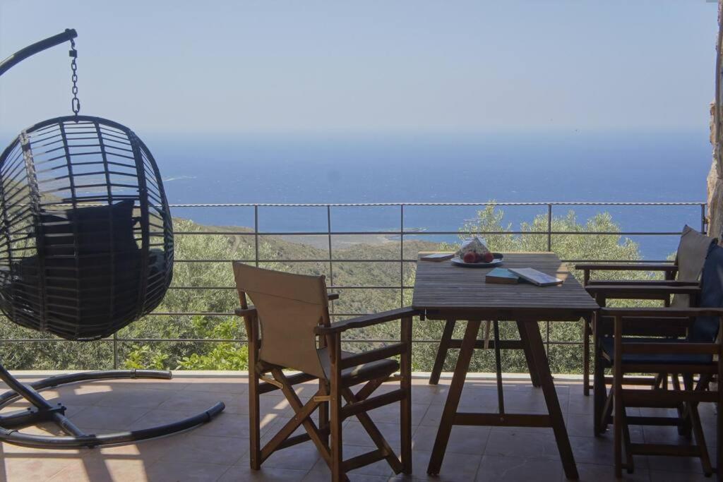 un tavolo e sedie su un balcone con vista sull'oceano di Rosales stone house ad AmigdhalokeFálion